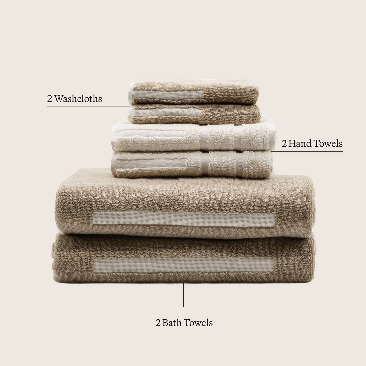 Stacked tan and ecru cotton towels with stitched stripe accents, plush textured pile.
