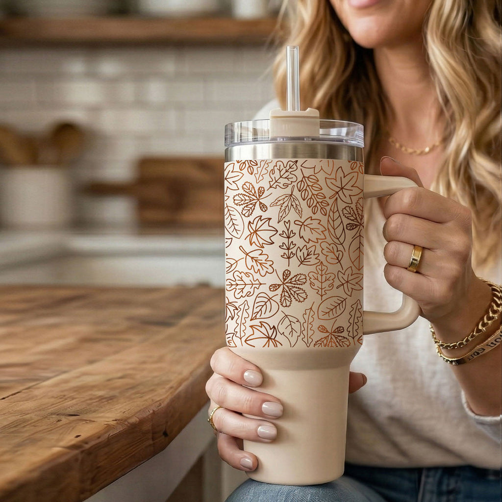 40oz cream tumbler with handle, clear lid, straw, and orange leaf line design.