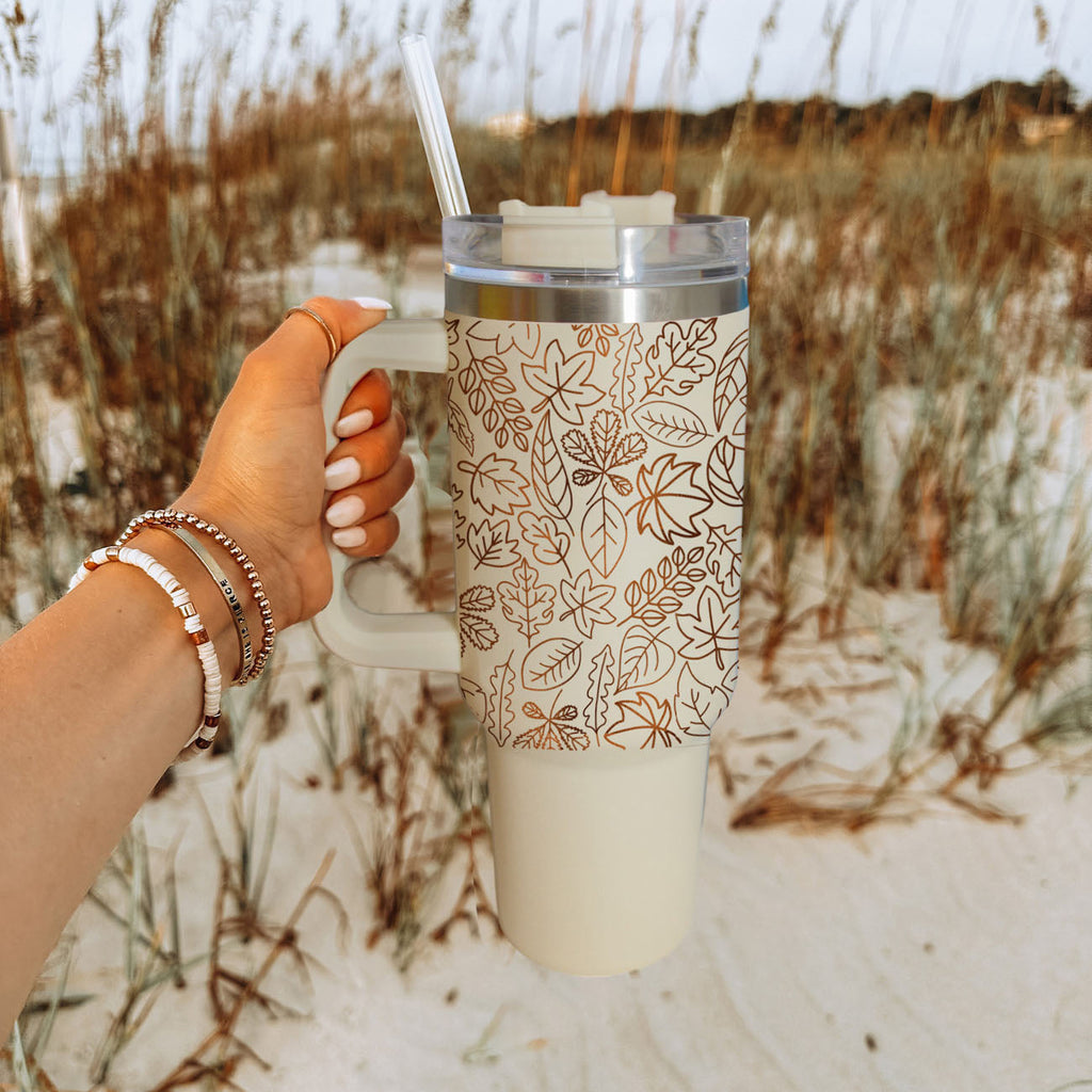 40oz cream tumbler with handle, clear lid, straw, and orange leaf line pattern.