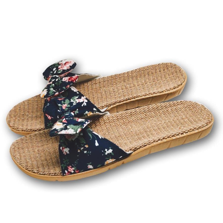Women's woven slide sandals with black floral knot strap and tan base, open toe
