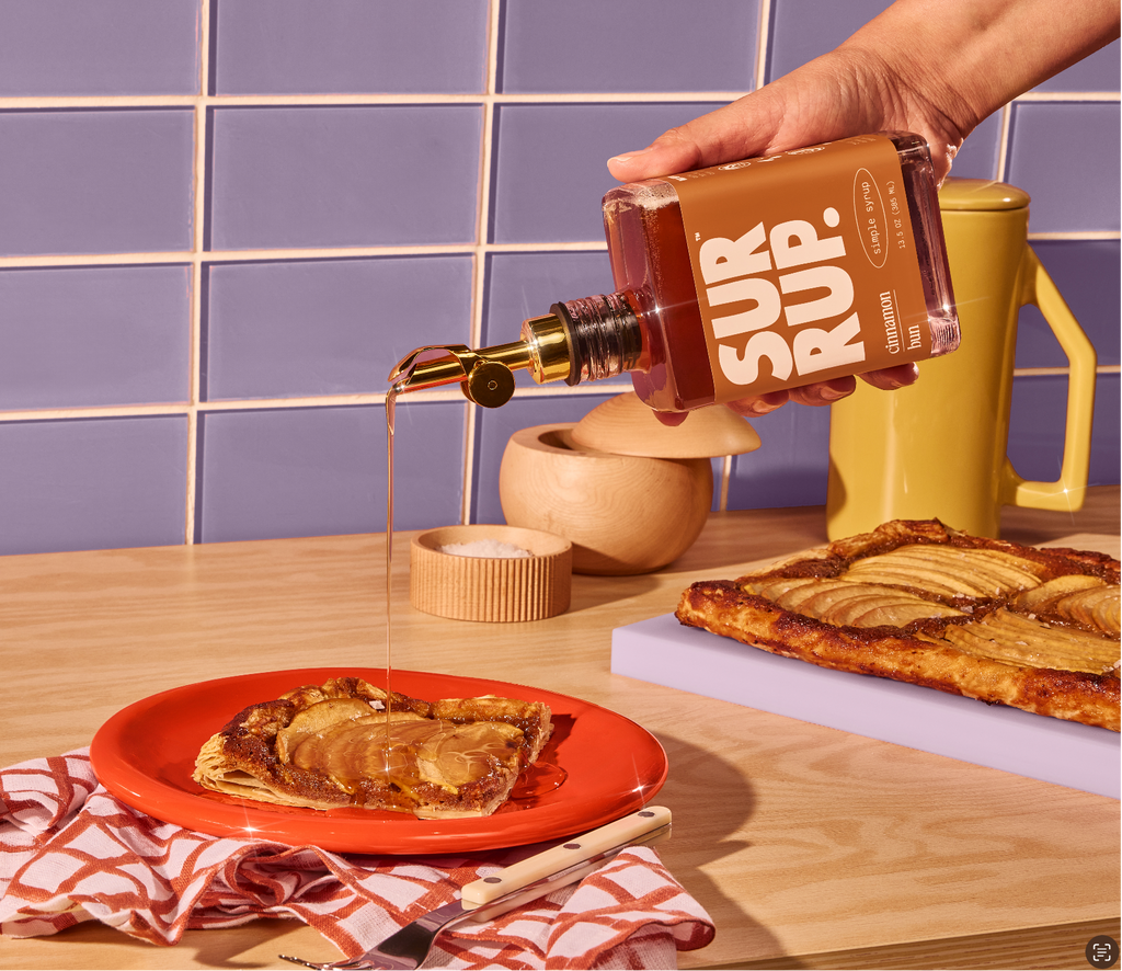 Syrup bottle pouring over sliced cinnamon bread on a red plate.