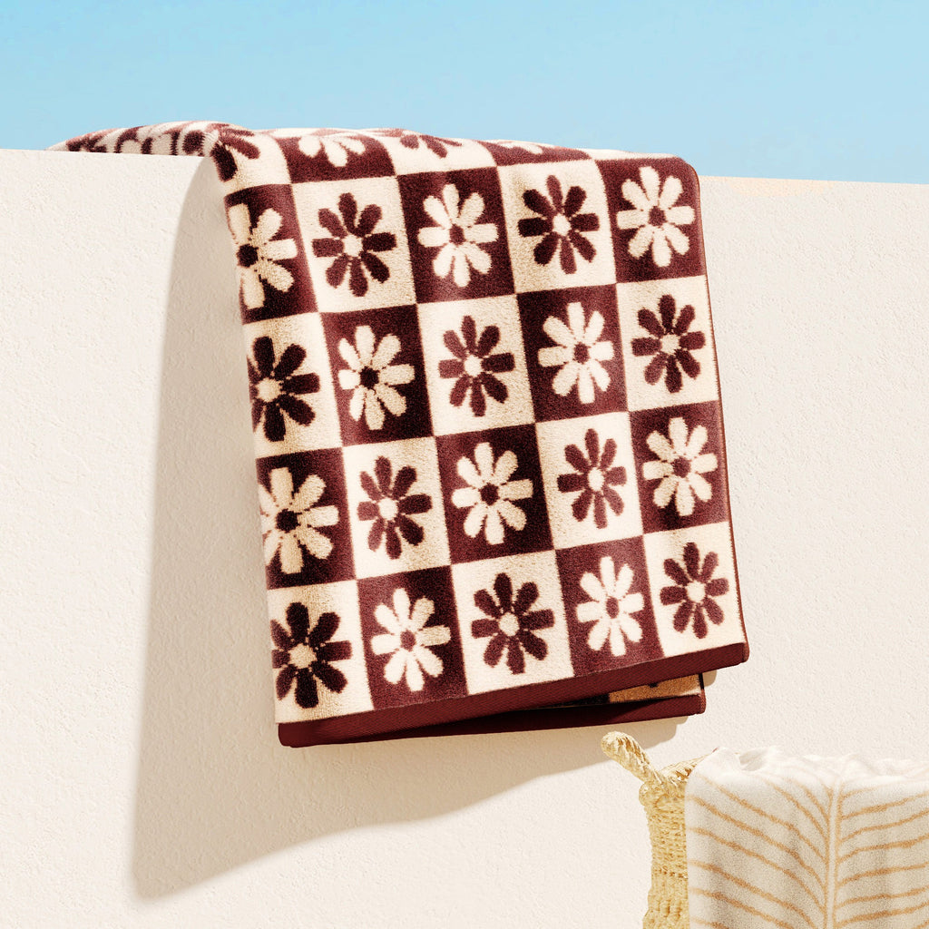 Cotton velour beach towel with brown, cream, and maroon check floral pattern, folded.
