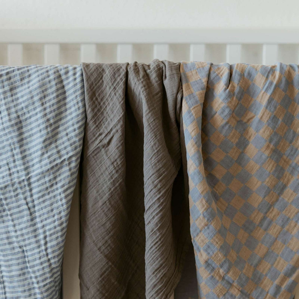 Stormy swaddle set swaddles hanging side by side: blue striped, gray solid, and tan checked