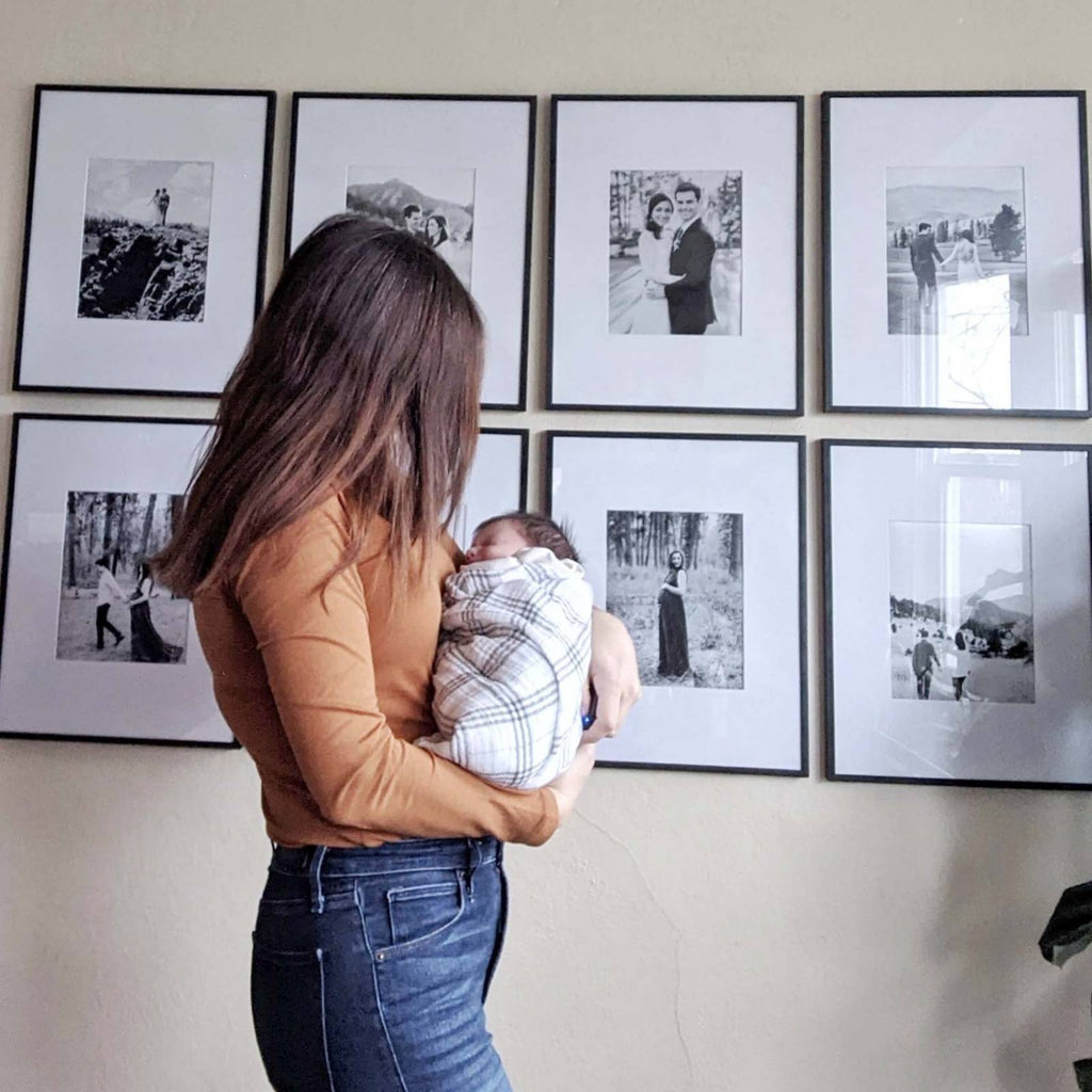 Baby held against shoulder in a plaid swaddle blanket