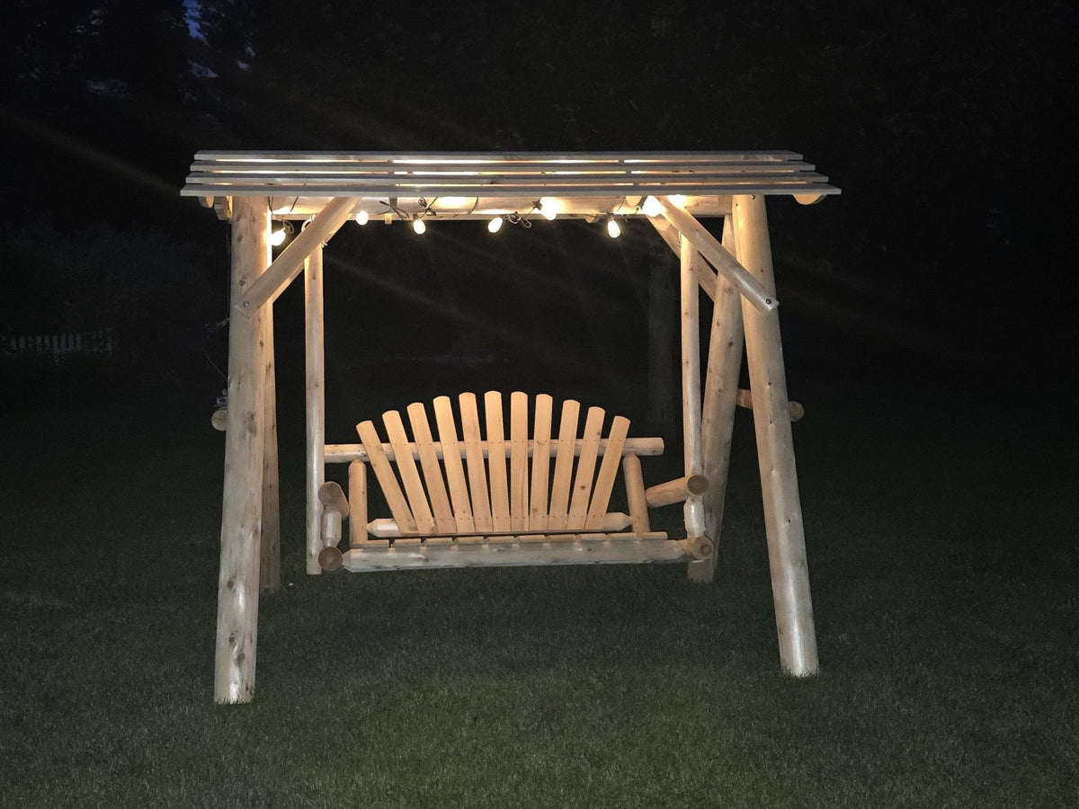 Wooden porch swing under canopy with warm string lights