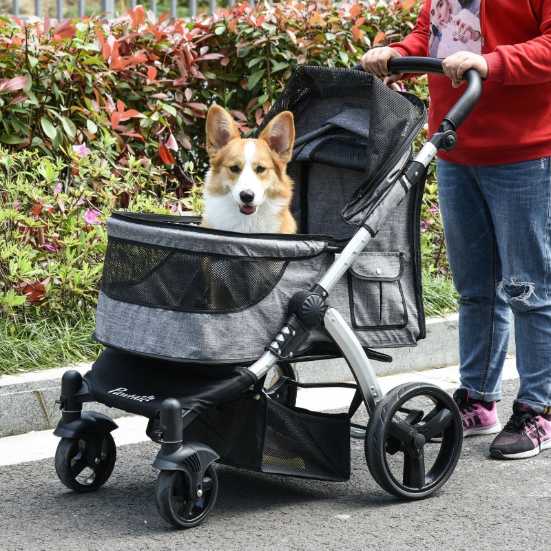 Gray pet stroller with mesh front window; corgi sits inside while handle is held.