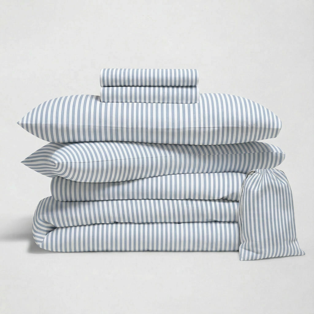 Blue striped sateen bedding bundle with layered duvets and rolled fabric throw
