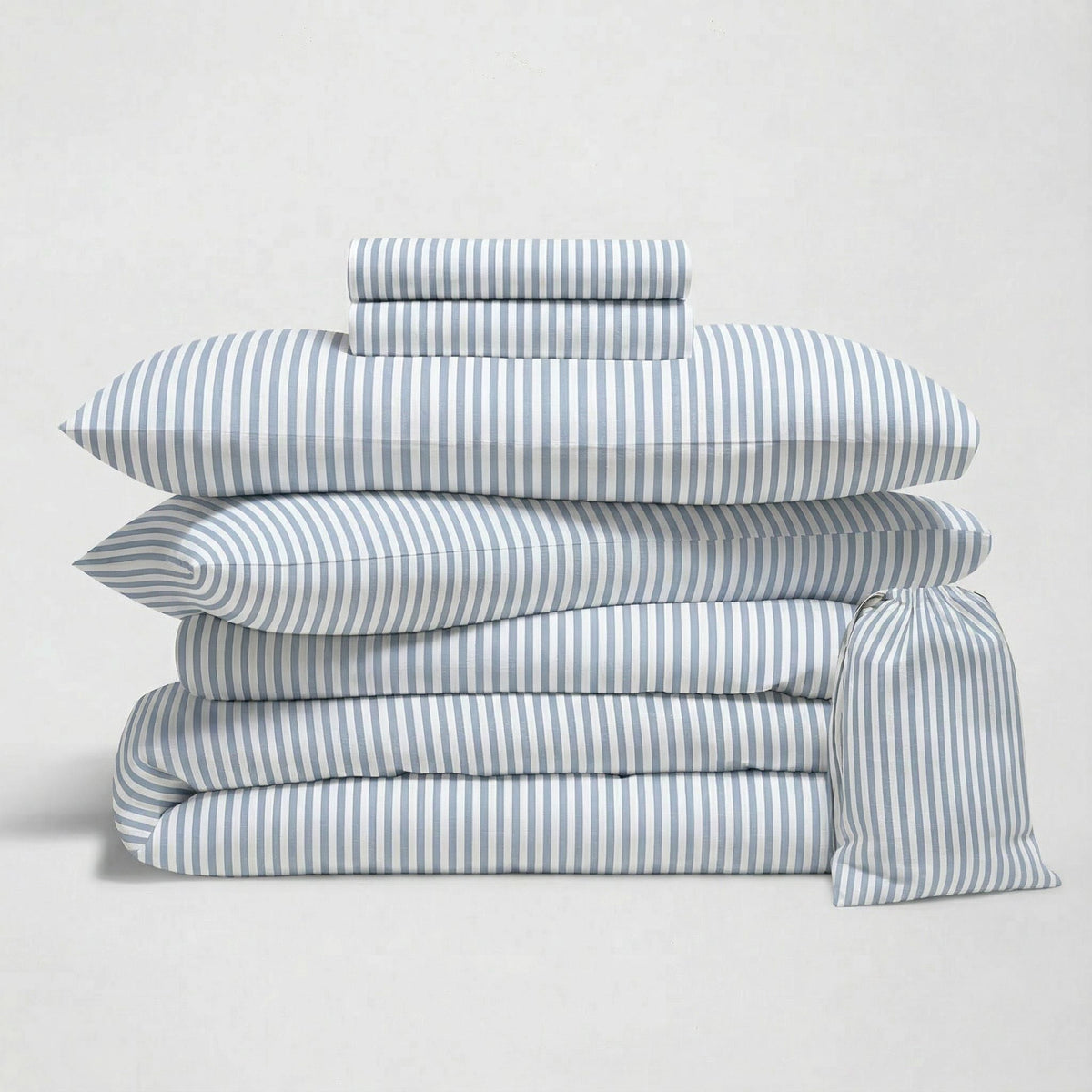 Blue striped sateen bedding bundle with layered duvets and rolled fabric throw