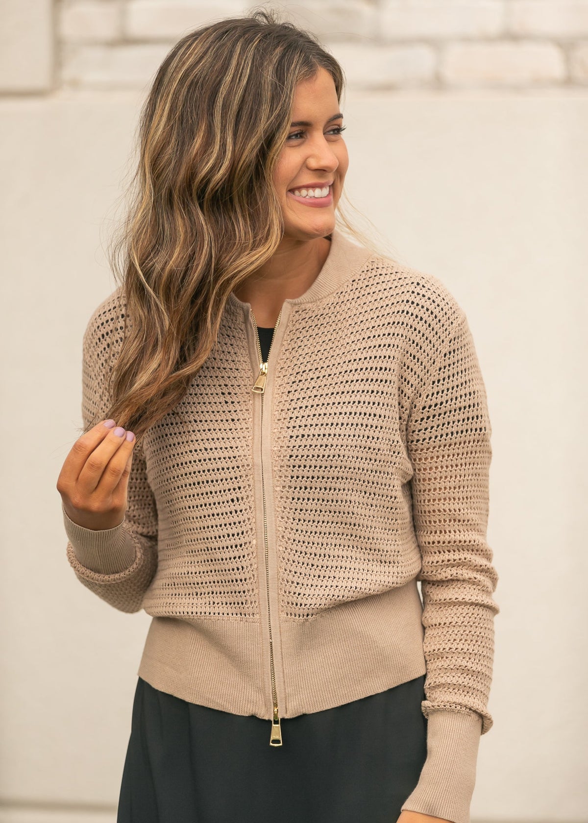 Three-quarter view of beige open-knit zip cardigan with long sleeves and ribbed trim.