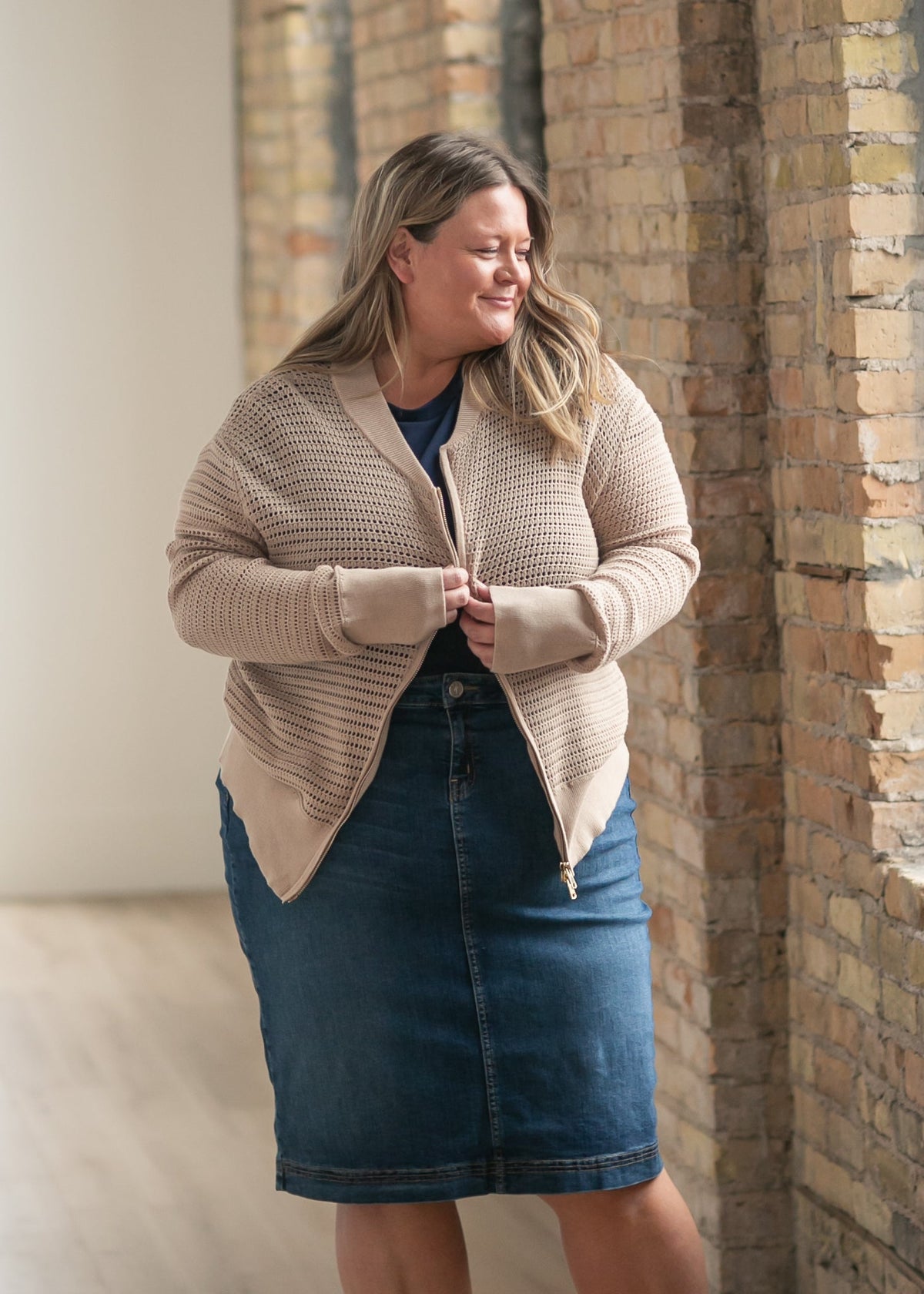 Beige open-knit crochet cardigan with zip-front, worn over a blue denim skirt