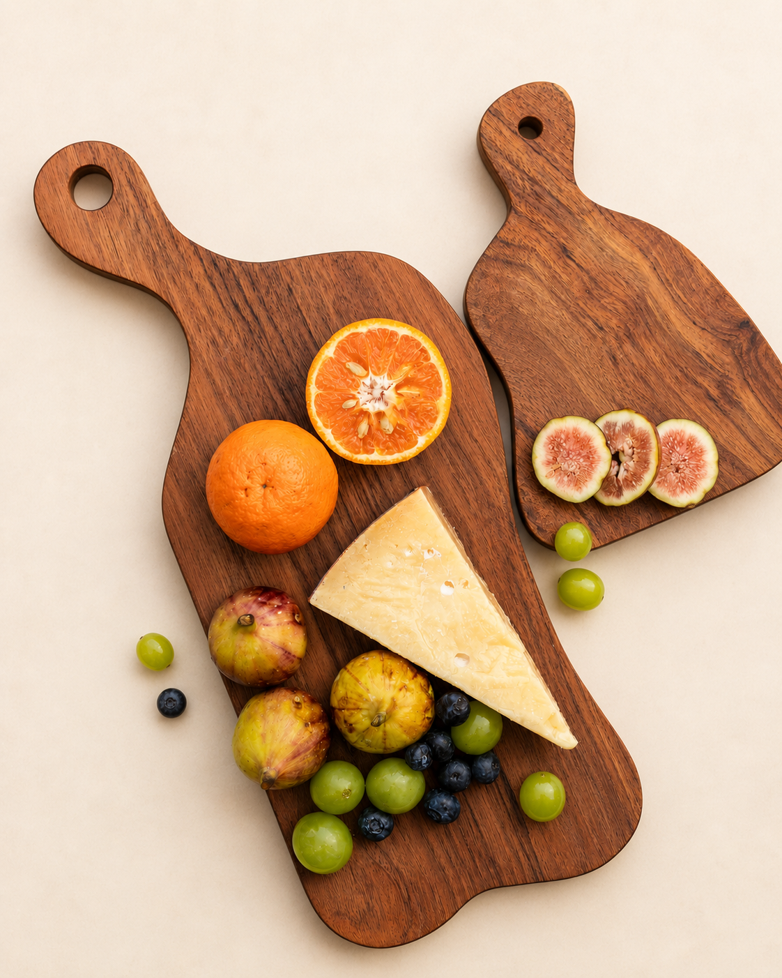 Teak wavy charcuterie boards topped with cheese and assorted fruit on two wooden shapes