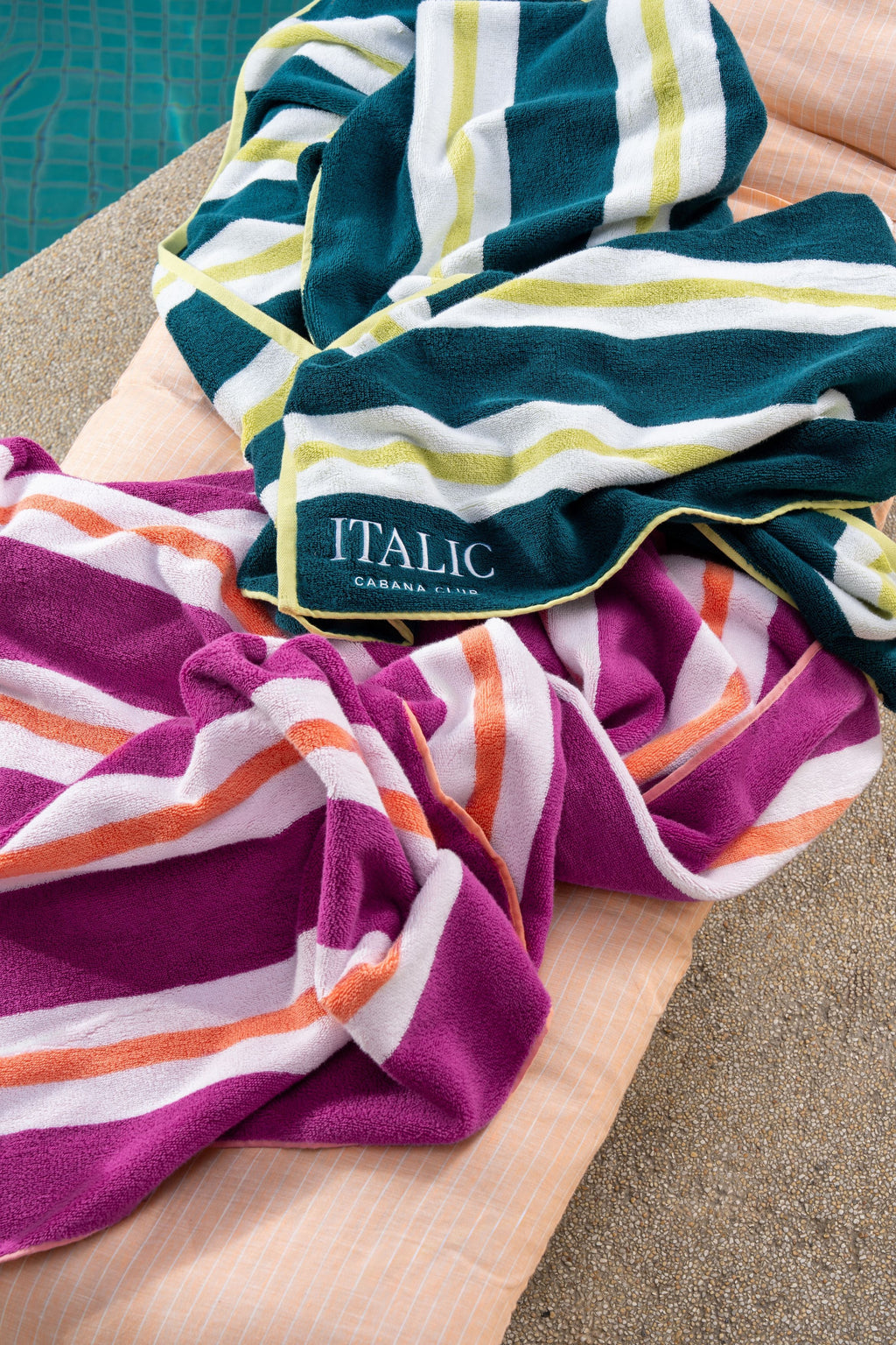 Pink, white, and coral striped cotton beach towel with terry border, folded up close.