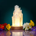 Selenite crystal lamp with glowing white mineral tower on round wooden base