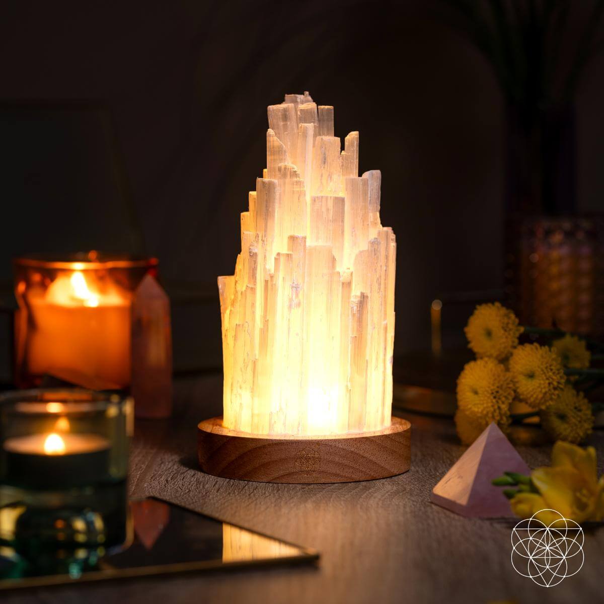 Warm-lit selenite crystal lamp on a round wooden base, glowing mineral tower