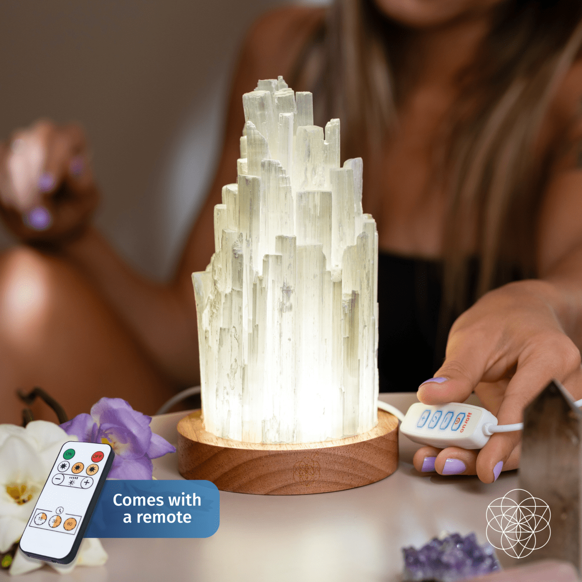 Glowing selenite lamp with white crystal tower and round wooden base