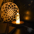 Healing lamp with faceted crystal point on round wooden base, lit candle glow