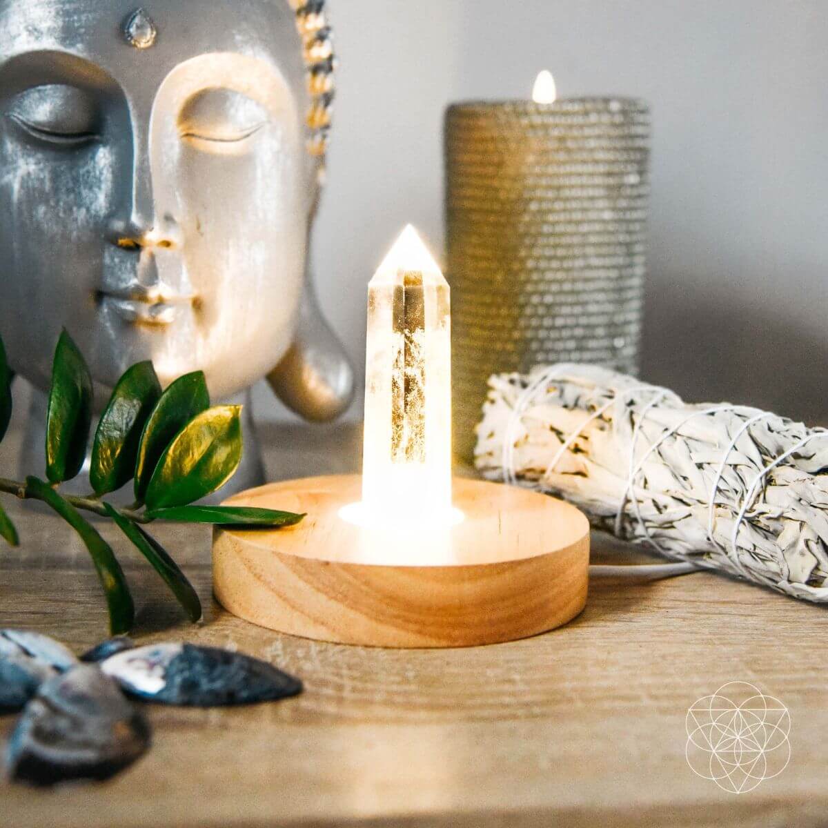 Healing lamp with crystal point on round wooden base, lit and styled with decor