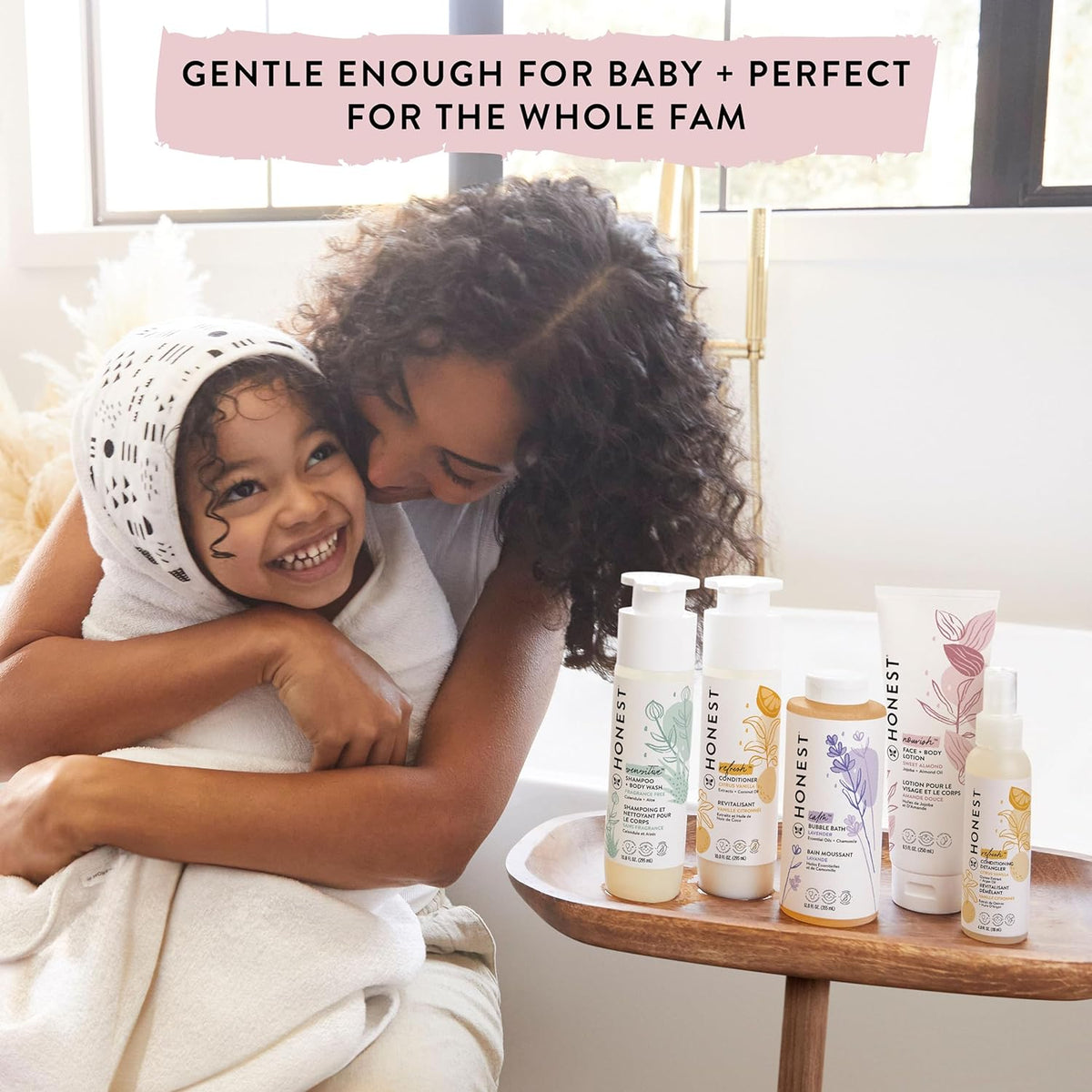 Honest 2-in-1 shampoo & body wash bottles on table next to smiling child and parent