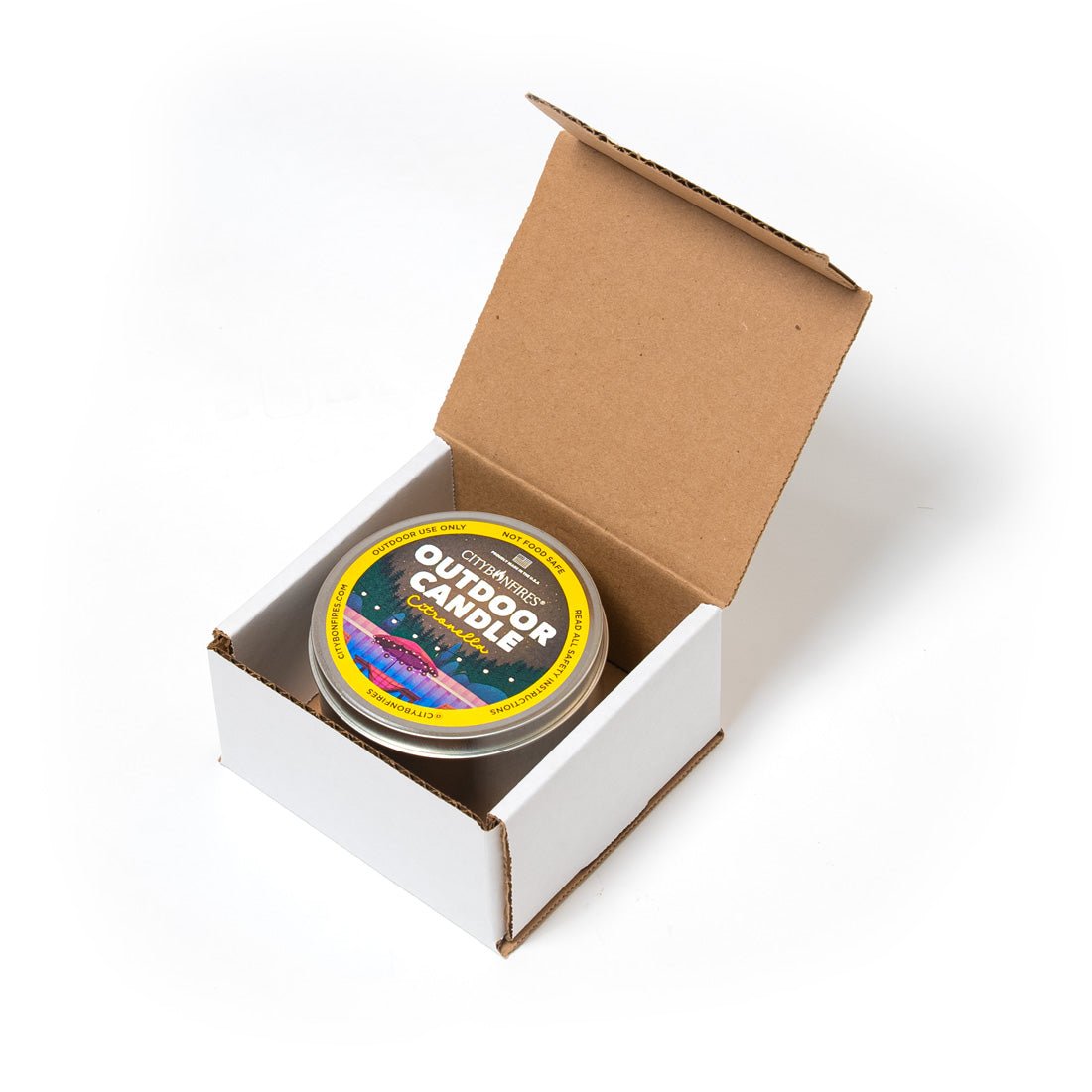 Outdoor citronella candle in metal tin placed inside an open cardboard box