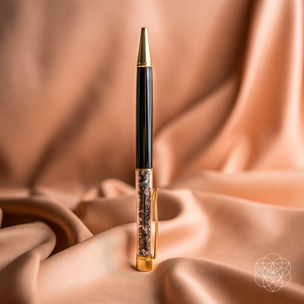 Self-cleansing crystal pen with gold body, standing upright on a draped fabric surface
