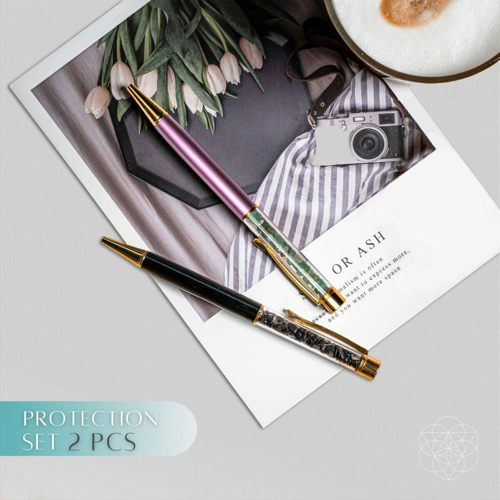 Protection set crystal pen with gold details and pink barrel, resting on stationery
