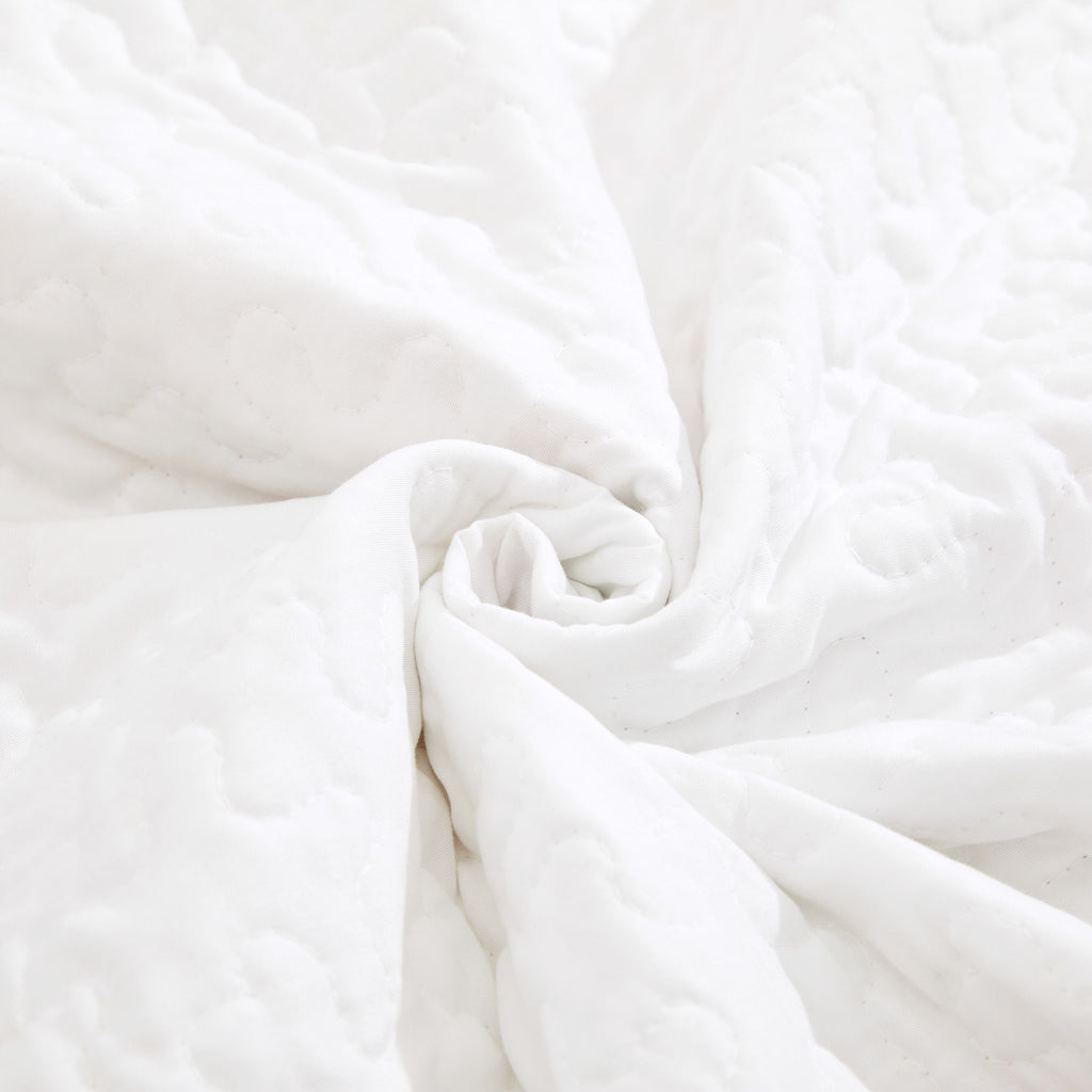 White quilted throw blanket with embossed texture and folded corner