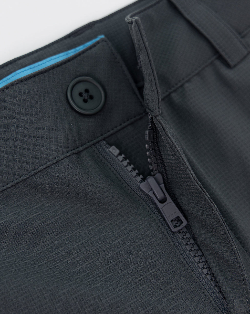 Dark gray sportswear shorts close-up of button, zipper, and pocket seam