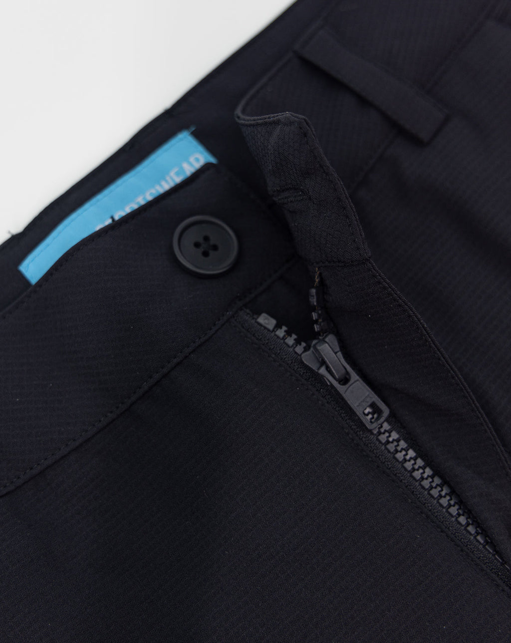 Dark fabric sportswear shorts close-up with button and metal zipper