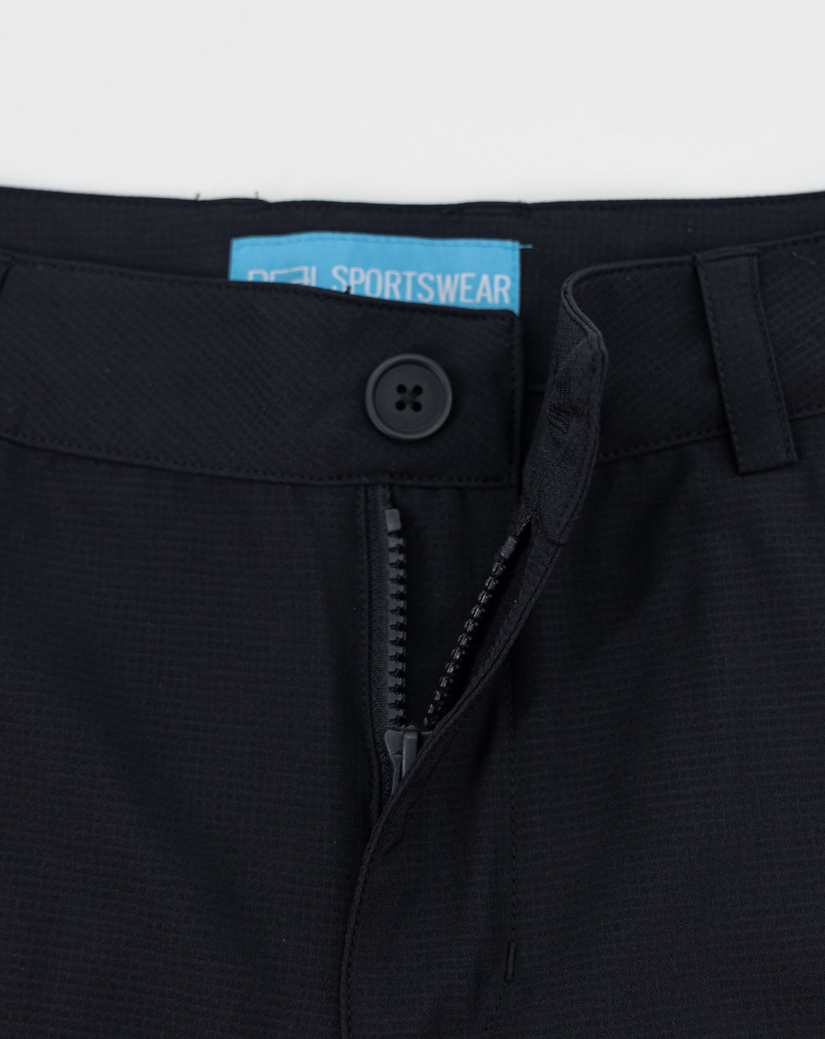 Dark sportswear shorts waistband close-up with button and hidden zipper