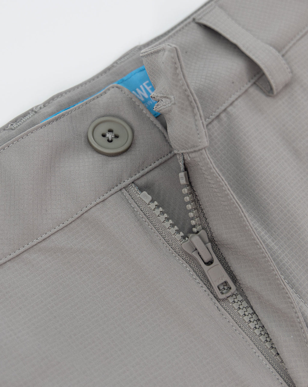 Light gray shorts close-up: zipper fly, button, and fabric tag