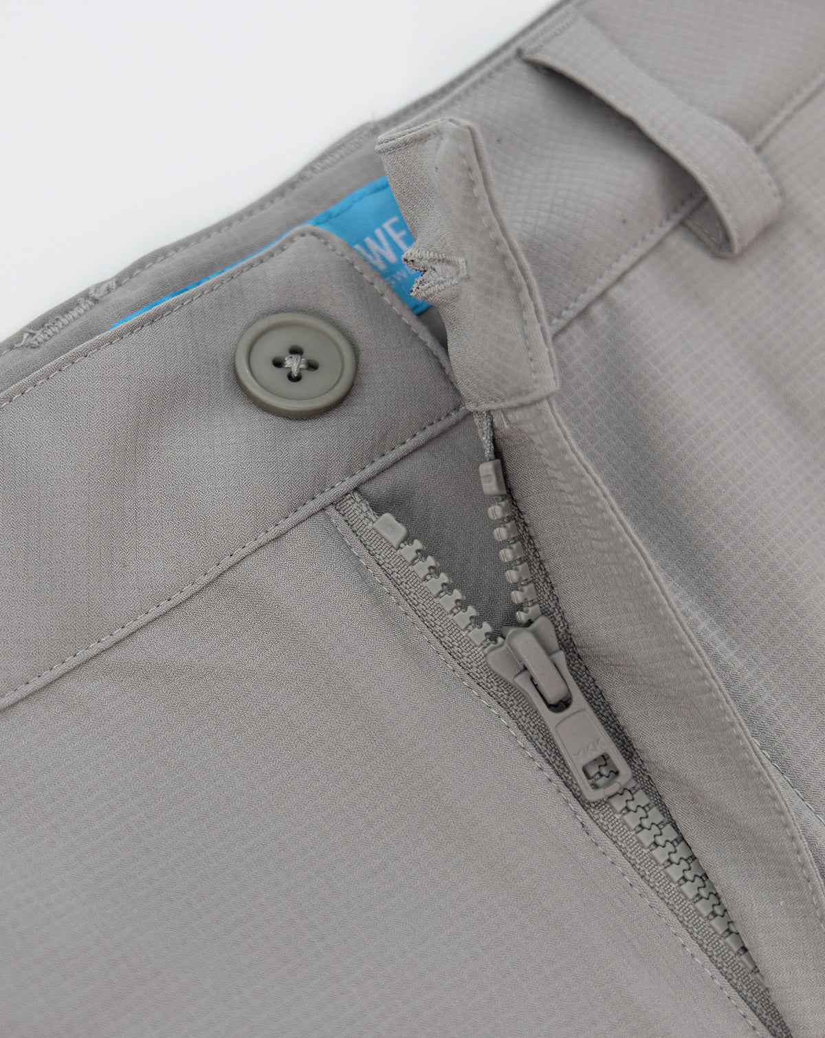 Light gray shorts close-up: zipper fly, button, and fabric tag