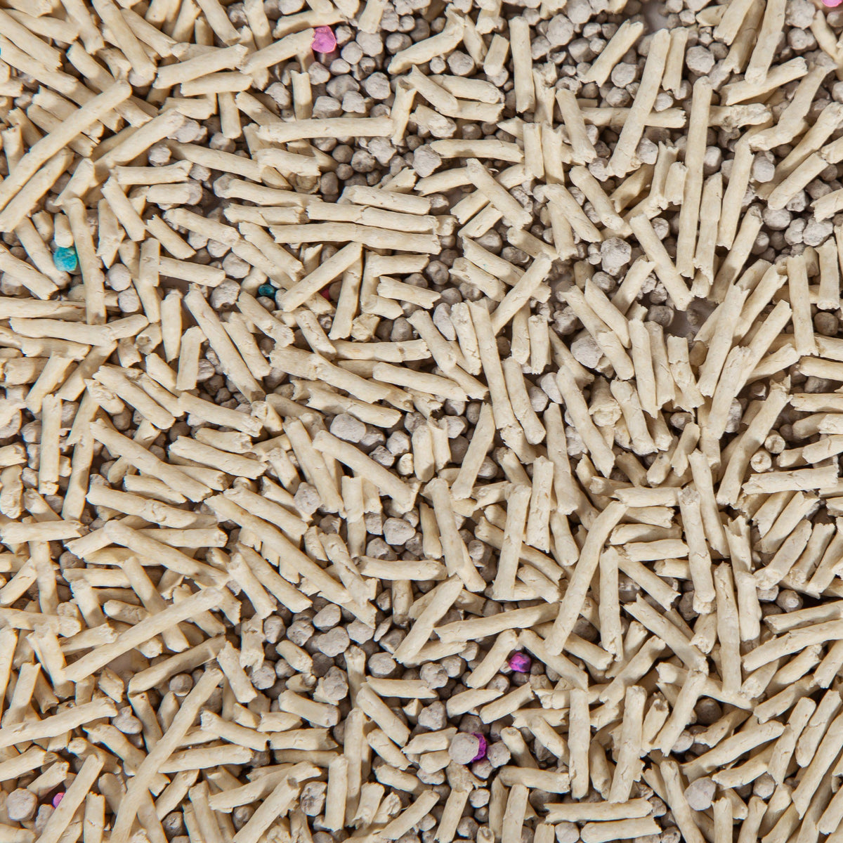 Close-up of mixed pale pellets and small colored granules in cat litter