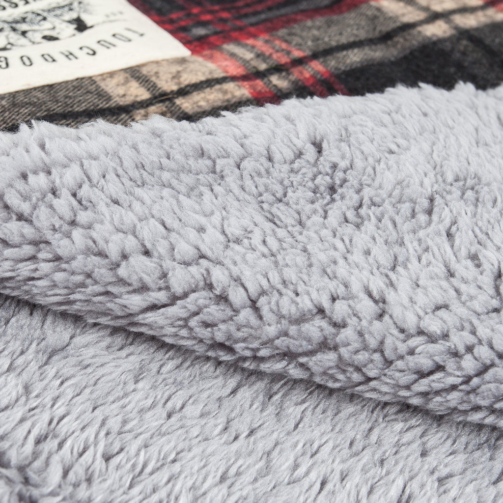 Reversible dog mat with a soft gray plush surface and tartan plaid edge