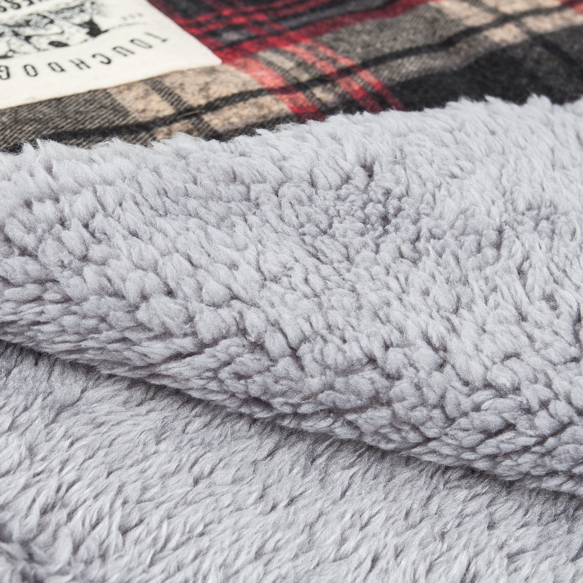 Reversible dog mat with a soft gray plush surface and tartan plaid edge