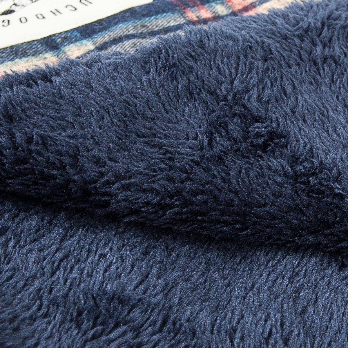 Reversible dog mat with a plush navy surface and tartan plaid edge