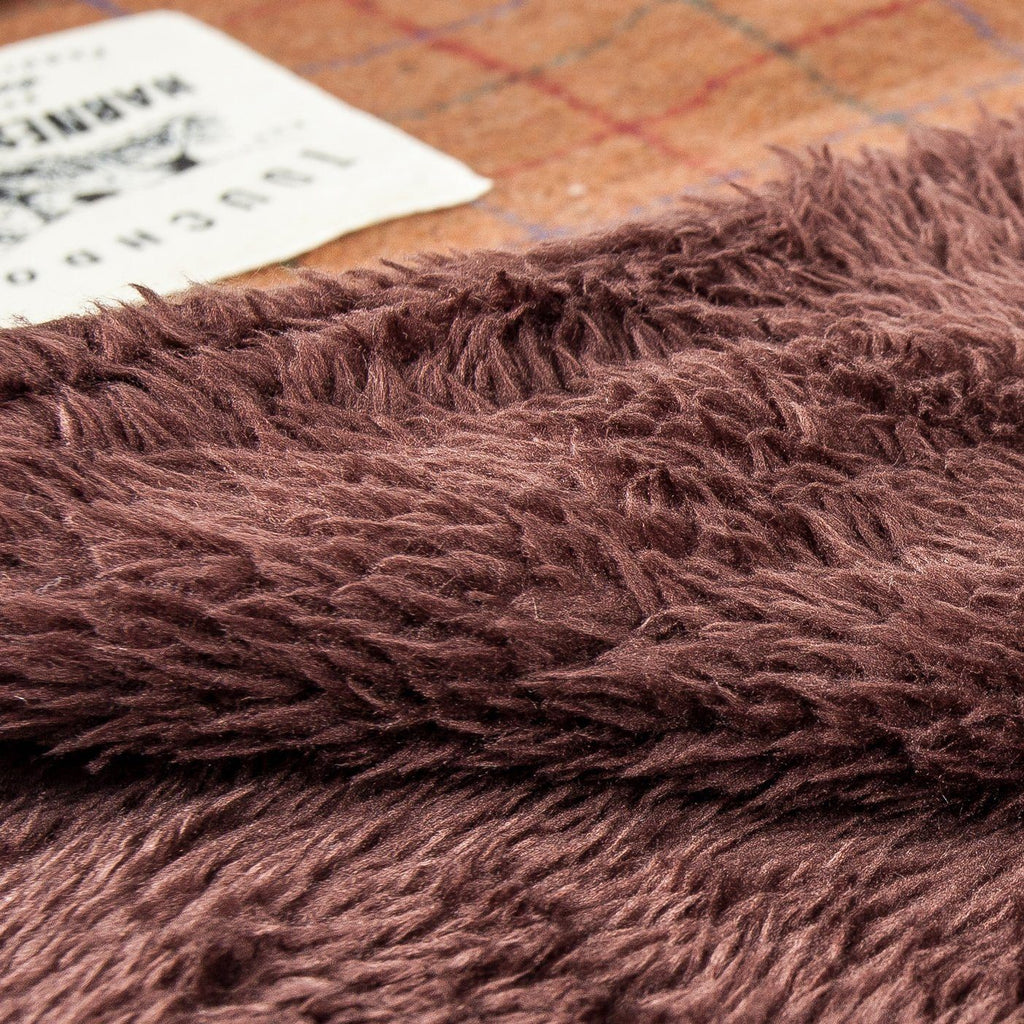 Reversible dog mat with a dark brown shaggy pile and raised folded edge