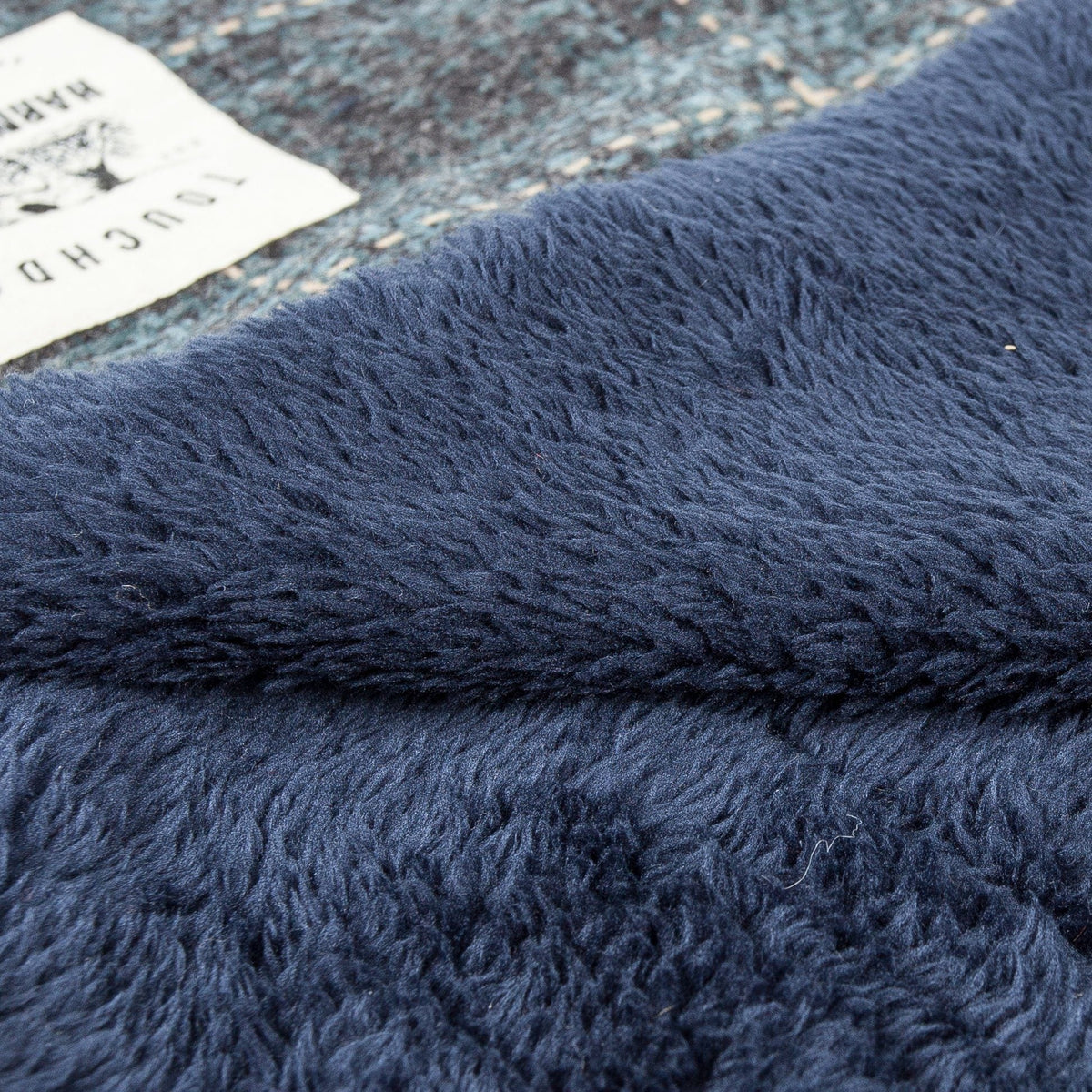 Touchdog mat close-up showing soft navy fleece beside the plaid woven fabric