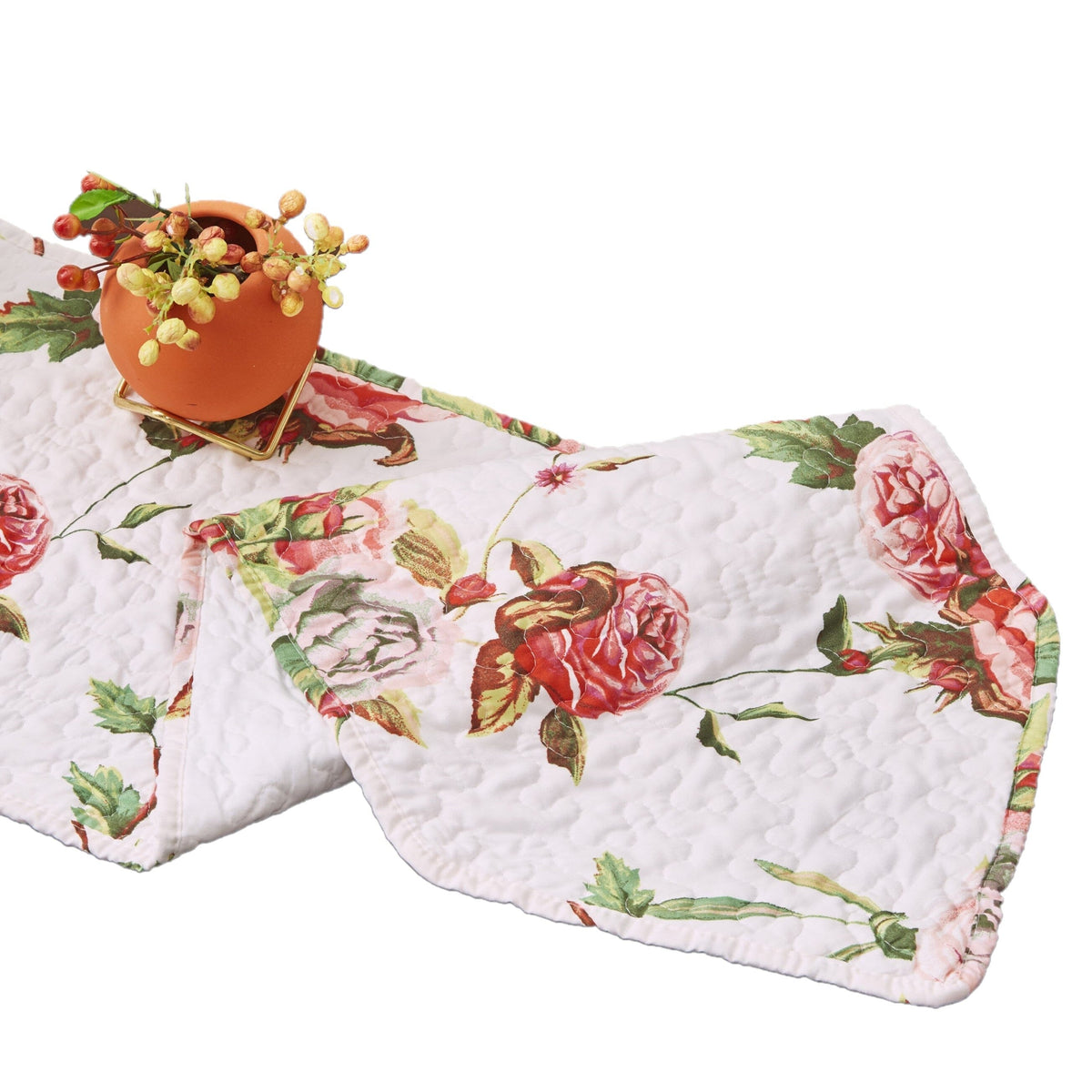 Quilted white table runner with pink rose floral print and green vine accents.