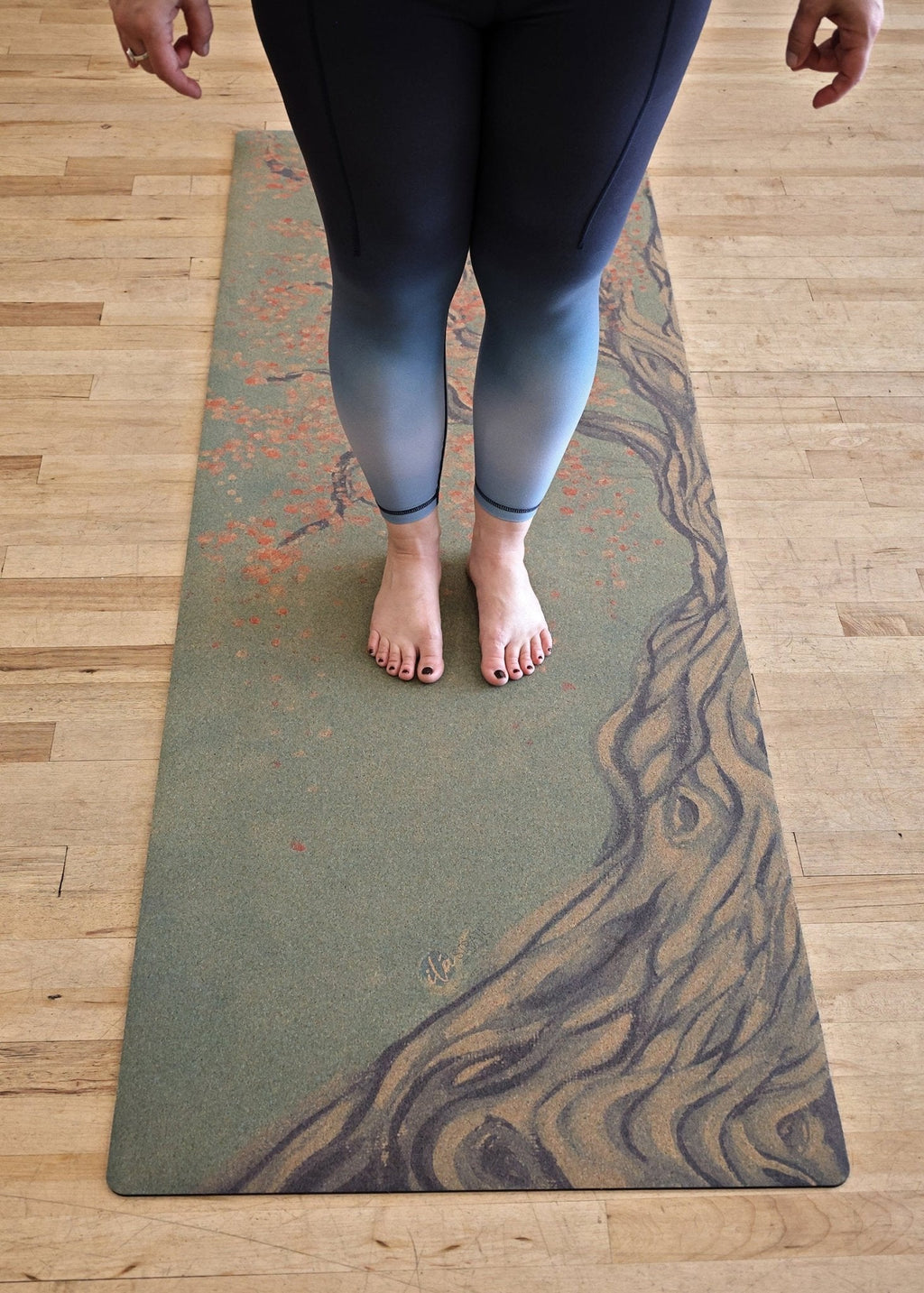 Cork yoga mat with tree artwork, shown beneath a person standing barefoot