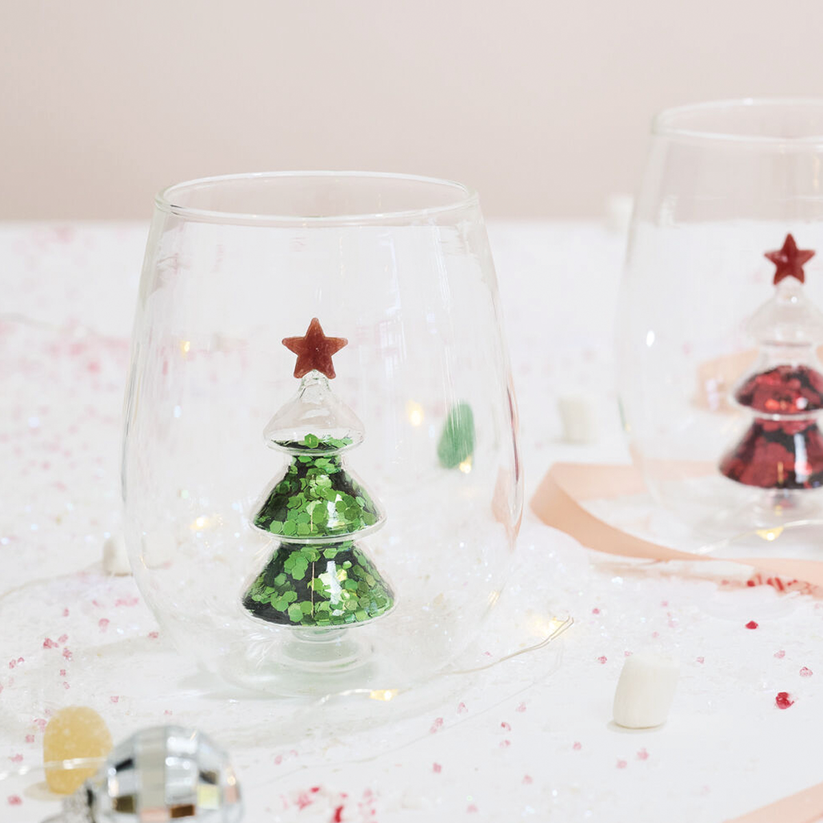 Clear stemless glass with embedded green glitter Christmas tree and red star topper