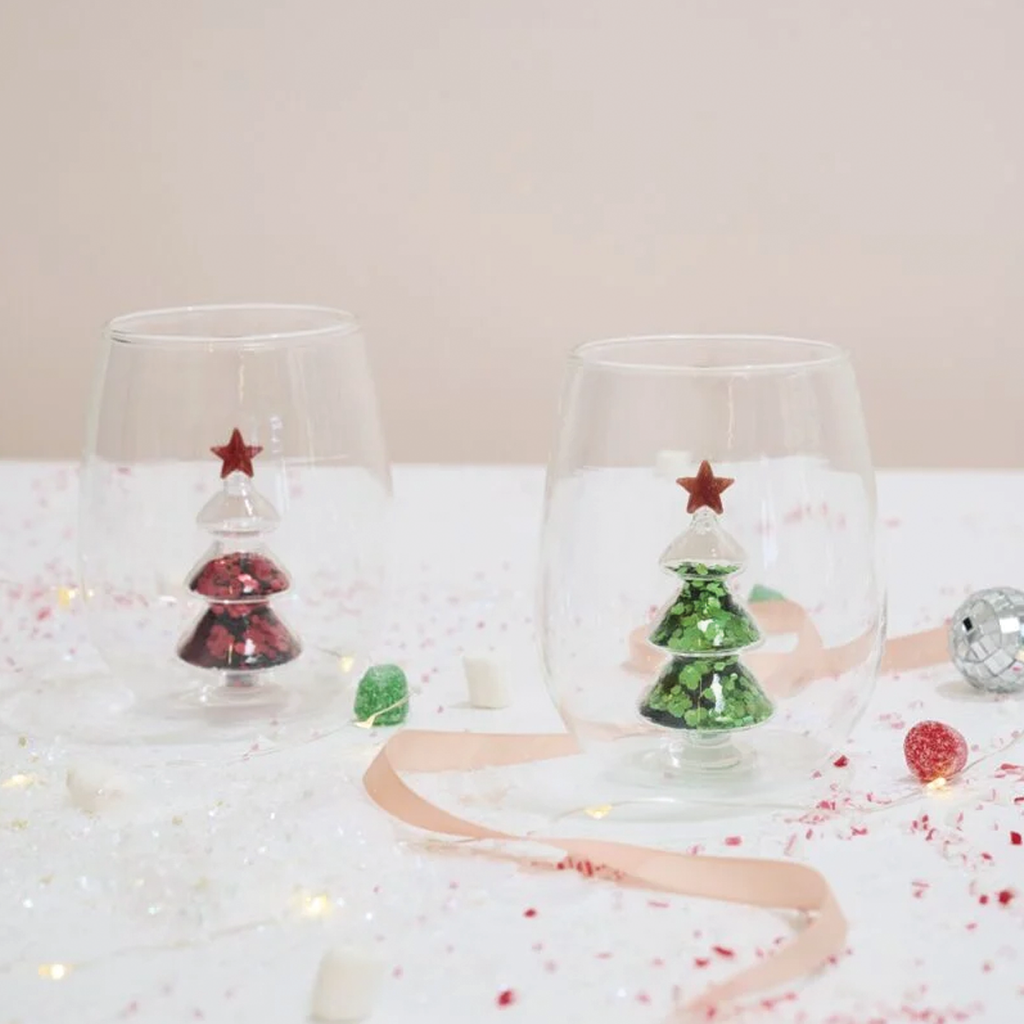 Pair of clear stemless glasses with green glitter trees and red star accents