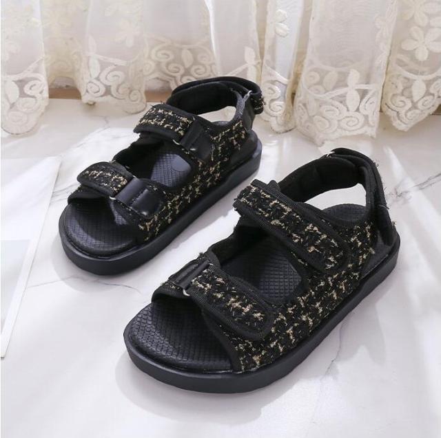 Black flat sandals with textured strap panels, hook-and-loop closures, and grippy sole
