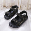 Black flat sandals with textured strap panels, hook-and-loop closures, and grippy sole