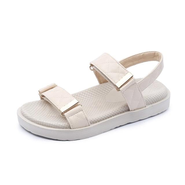 Beige flat open-toe sandals with two wide straps and metal buckle details