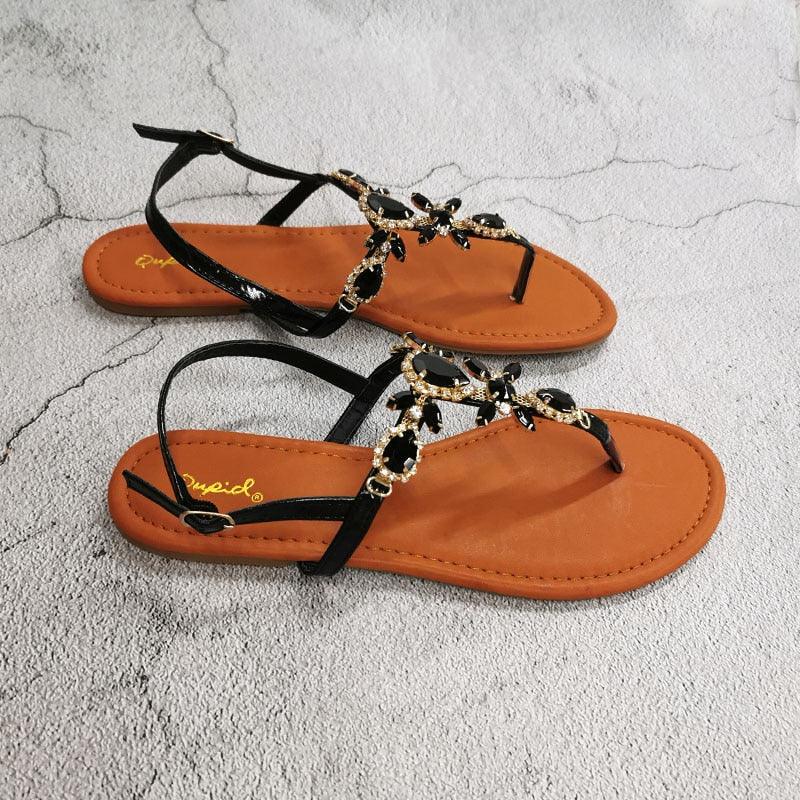 Black flat open-toe sandals with black straps and gold-tone rhinestone flower ornaments