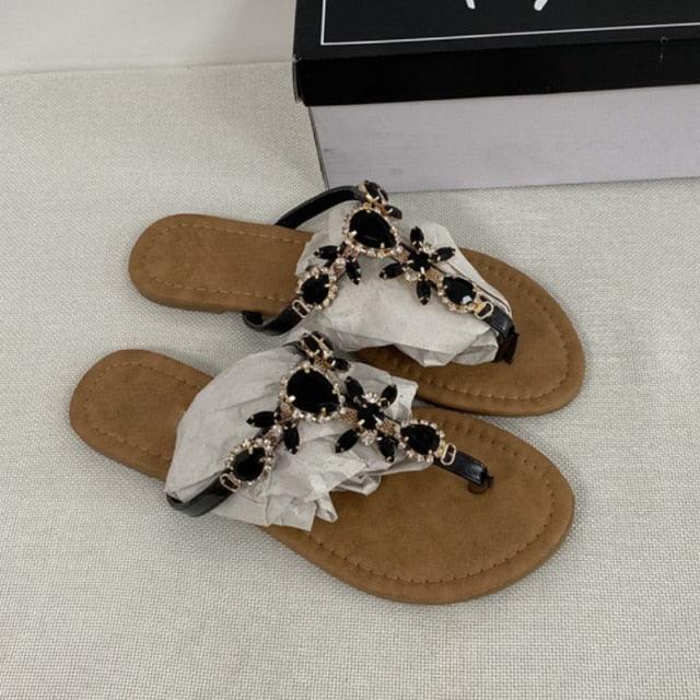 Tan flat open-toe sandals with black rhinestone embellishments and crisscross straps