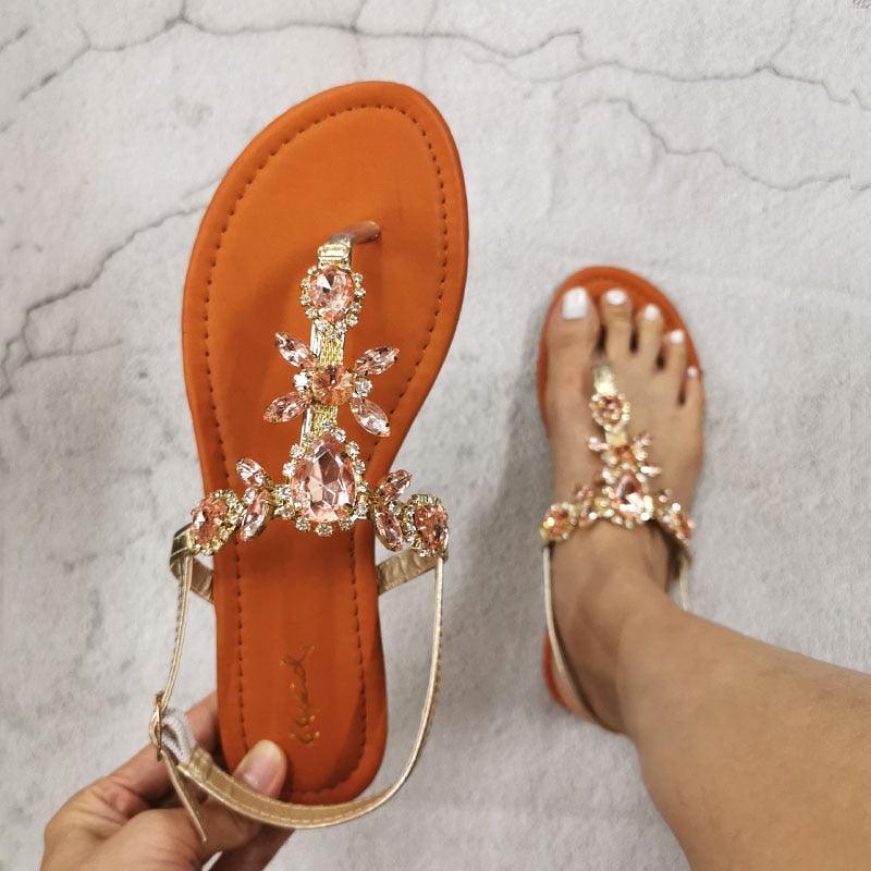 Orange flat open-toe sandals with rhinestone flower straps and back strap, jeweled detail