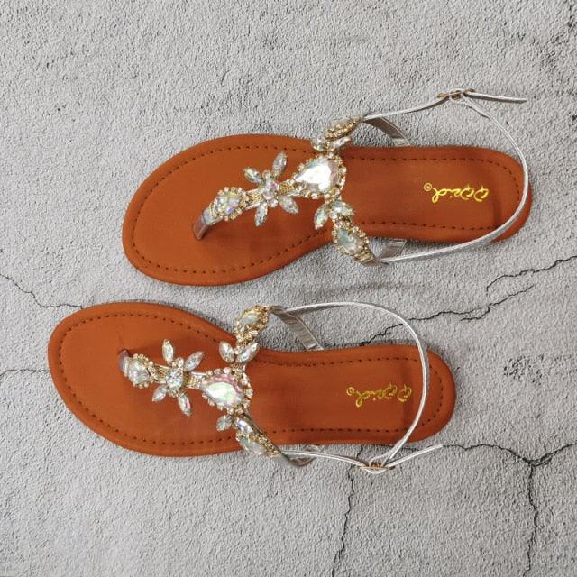 Gold flat open-toe sandals with rhinestone flower embellishments and thin ankle ties
