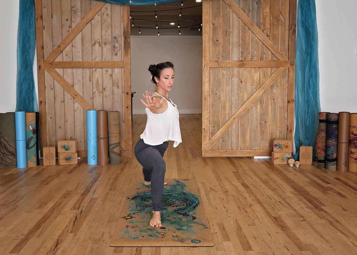 Cork yoga mat with a blue-green turtle design, shown beneath a person in a yoga pose
