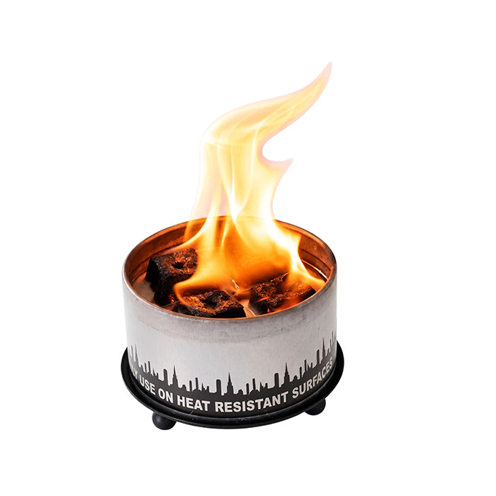 Gray candle trivet holding a burning candle, skyline print on the metal rim